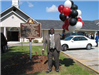 Pastor Holding balloons in front of the sign
