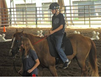 Woman leading a horse with a child rider